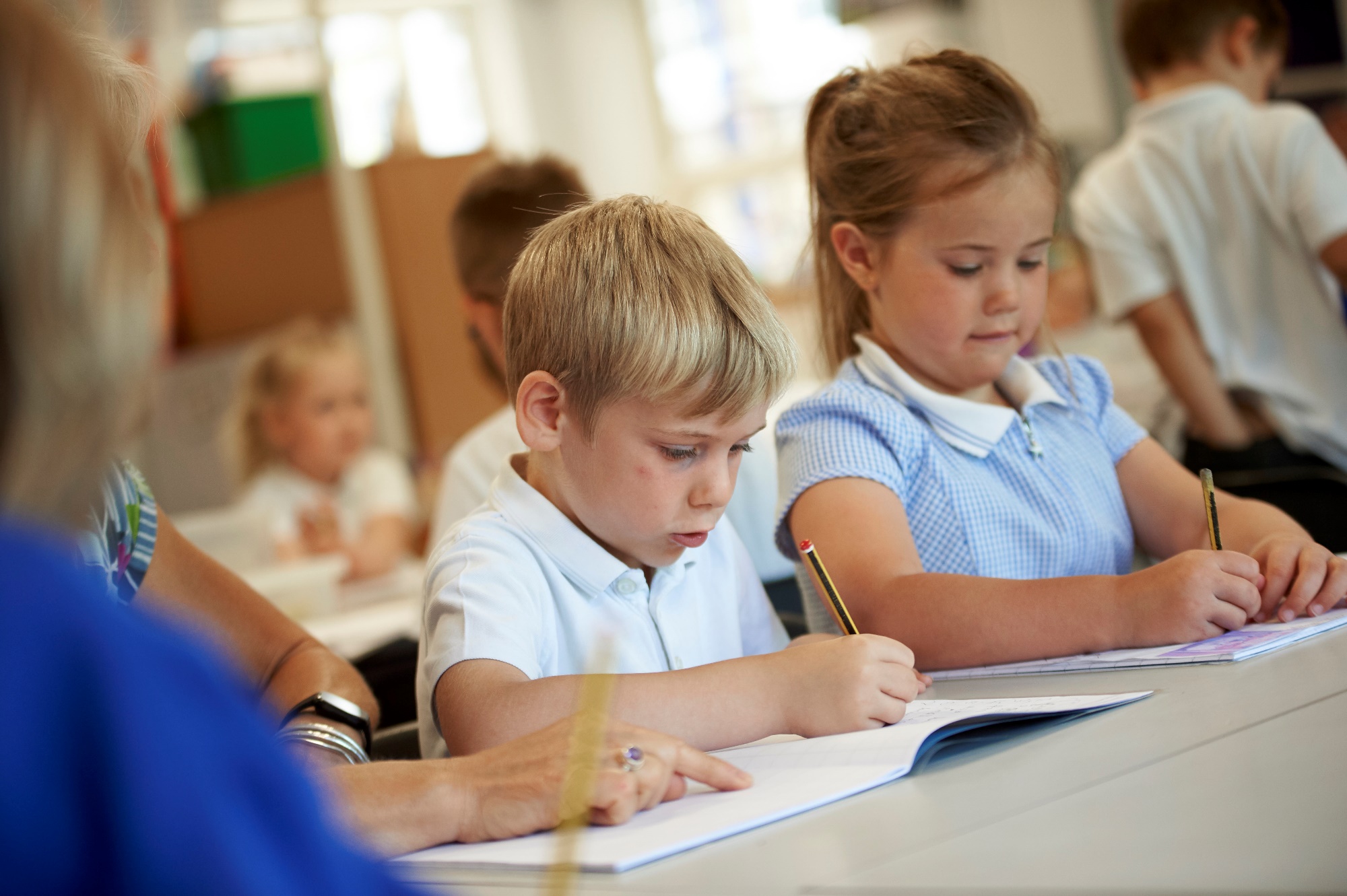 Image of children writing at their desks in the classsroom